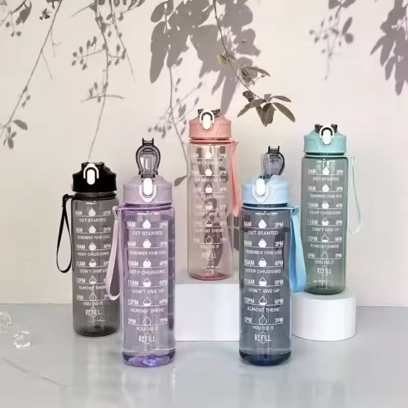 Five motivational water bottles of different colors on a light surface with a floral background.